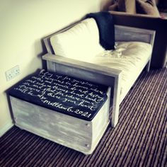 a bed with a wooden frame and writing on the bottom shelf next to a pillow