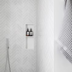 a white bathroom with herringbone wallpaper and shelf for soaps, lotion and hand sanitizers