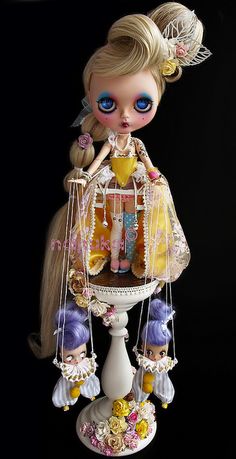 a doll is sitting on top of a carousel with dolls hanging from it's sides