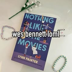 a book sitting on top of a white table next to bracelets and a flower