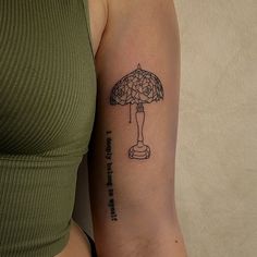 a woman with a tattoo on her arm has an umbrella in the shape of a lamp