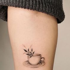 a tattoo on the leg of a woman with a cup and saucer in it