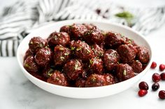 a white bowl filled with meatballs and garnished with cranberry sauce