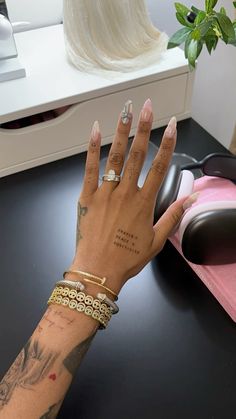 a woman's hand with tattoos on her left arm and two gold bracelets