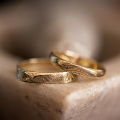 two gold wedding rings sitting on top of a rock