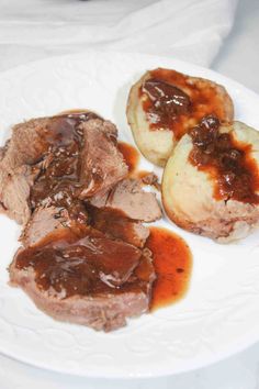 a white plate topped with meat and potatoes covered in gravy