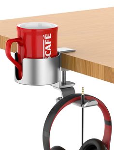 a red coffee cup sitting on top of a table next to a black and white wheel