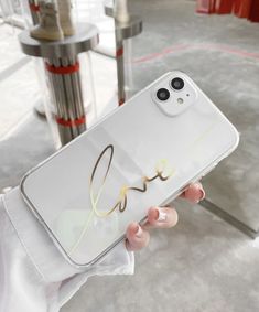 a person holding up a white phone case with the word love written in cursive writing on it