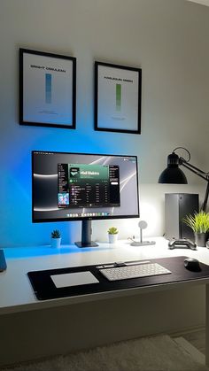 a desk with a computer monitor, keyboard and mouse next to two pictures on the wall