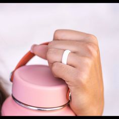 a woman holding onto a pink cup with a ring on it