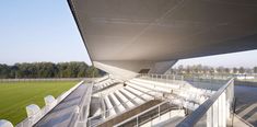 an empty stadium with white seats and railings on the side walk, overlooking a green soccer field