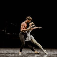 two ballet dancers performing on stage at night