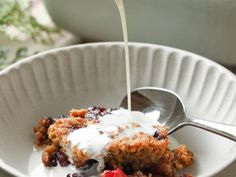 a white bowl filled with fruit cobbler next to a cup of yogurt