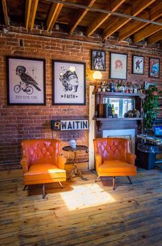 two orange chairs sitting next to each other in front of a wall with pictures on it