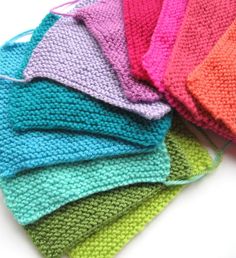 there are many colors of knitted cloths on the table