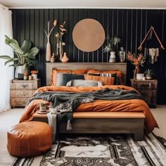 a bedroom with black walls and orange bedding in the center is decorated with potted plants