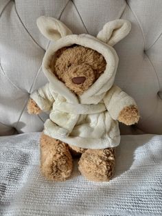 a teddy bear in a bunny costume sitting on a couch with a white cover over it