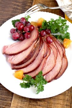 sliced ham and grapes on a white plate