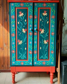 an old cabinet painted with flowers and leaves on it's sides, sitting in a room