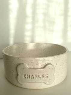 a white bowl with a dog bone on the front and wording that says charles