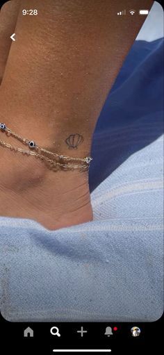 a woman's foot with a gold chain and evil eye bracelet on her ankle