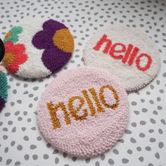 three personalized coasters on a polka dot tablecloth with the word hello written on them