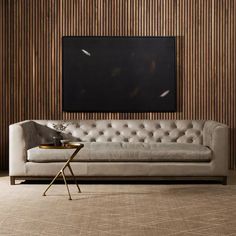 a white couch sitting in front of a wooden wall with a black painting on it