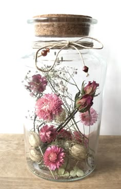 a glass jar filled with flowers on top of a wooden table