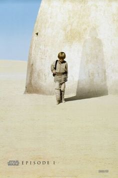 a man standing in front of a white structure on top of a sandy hill with a sky background