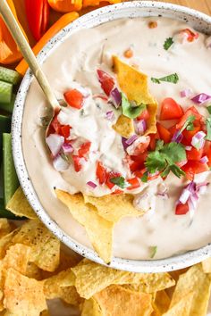 a white bowl filled with guacamole surrounded by tortilla chips and vegetables