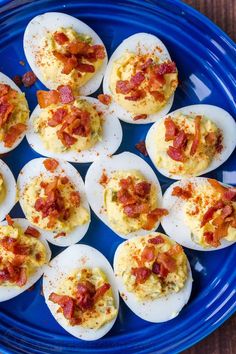 deviled eggs topped with bacon on a blue plate