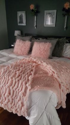 a large bed with pink fluffy pillows and blankets on it's headboard in a bedroom