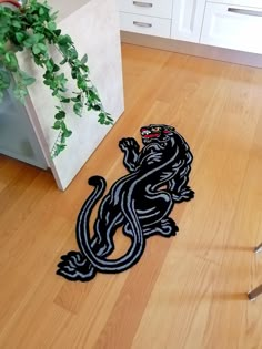 a black and white lizard on the floor next to a potted plant in a kitchen