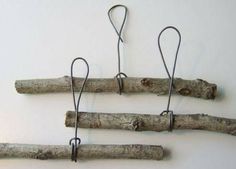 four pieces of wood are hanging from hooks on a white wall, with wire attached to them