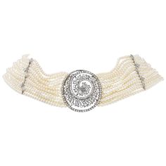 The thirteen strand cultured pearl collar necklace, with tubular slide-clasp ends, center highlights a platinum and diamond set spiral medallion, designed as a diamond set feather-edged spiral within the spiral's diamond set frame. Two knife-edged bards, one set with five single-cut diamond set leaf accents and one bar plain, stabilize the necklace at two points equally spaced between the medallion and clasp ends. Diamond Choker Necklace, Diamond Choker, Seed Pearl, Pearl Diamond, Collar Necklace, Cultured Pearls, Choker Necklace, Platinum, Diamond Cuts