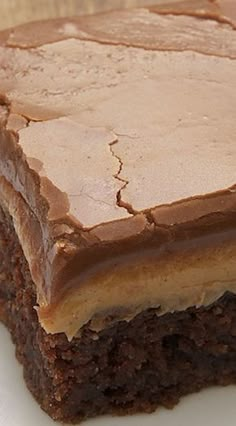 a piece of chocolate cake sitting on top of a white plate covered in frosting