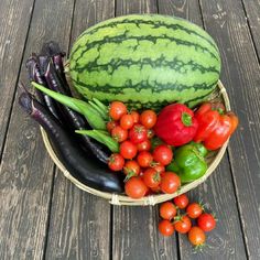 a basket filled with lots of different types of fruits and vegetables on top of a wooden table