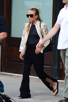 a man and woman are walking down the street holding hands with one another as they both wear sunglasses