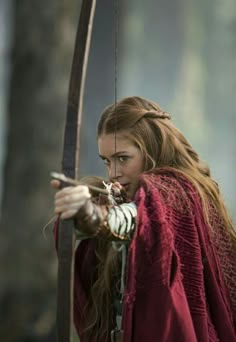 a woman with long hair is holding a bow and arrow