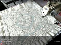 an image of a quilt being worked on by someone using scissors to sew it