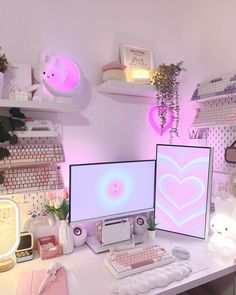 two computer monitors sitting on top of a desk next to each other in front of pink lighting