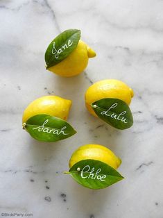 four lemons with green leaves and some words written on them, sitting on a marble surface