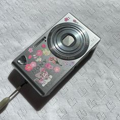 a camera with a flowered design on it sitting on top of a white blanket