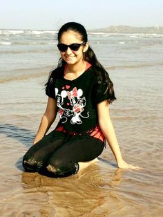 a woman sitting in the water on top of a sandy beach