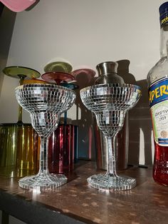 two wine glasses sitting on top of a wooden table next to a bottle of alcohol