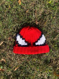 a red and white knitted hat laying in the grass