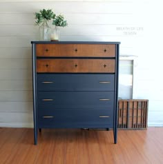 a dresser with some flowers in a vase sitting on top of it's drawers