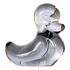 a clear glass duck sitting on top of a white surface