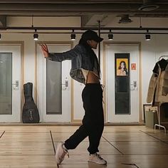 a young man is dancing in an empty room with guitars on the wall behind him