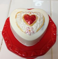 a heart shaped cake sitting on top of a red plate next to a white tile floor